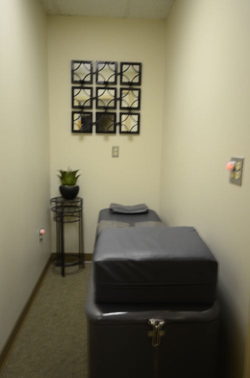 A treatment table in a clinical setting with medical equipment nearby