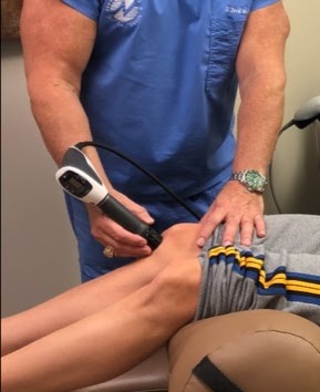 Dr. Nadler applies a shockwave therapy device to a patient's right leg.
