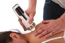 A woman receives shockwave therapy to her neck from a specialist. This is a close-up shot with no faces.