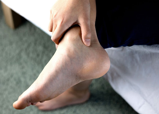 a person whit Achilles tendinopathy grabs their upper foot