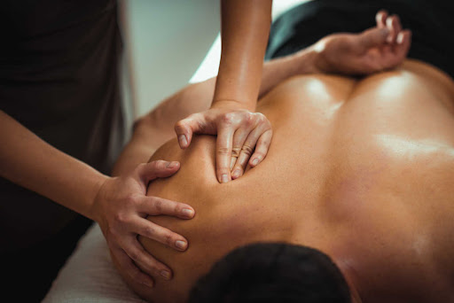 two hands perform massage therapy on a person's back