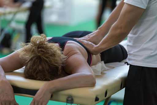 A person performs massage therapy on a person lying down face-first.